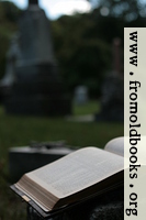 Open Bible and cross in graveyard